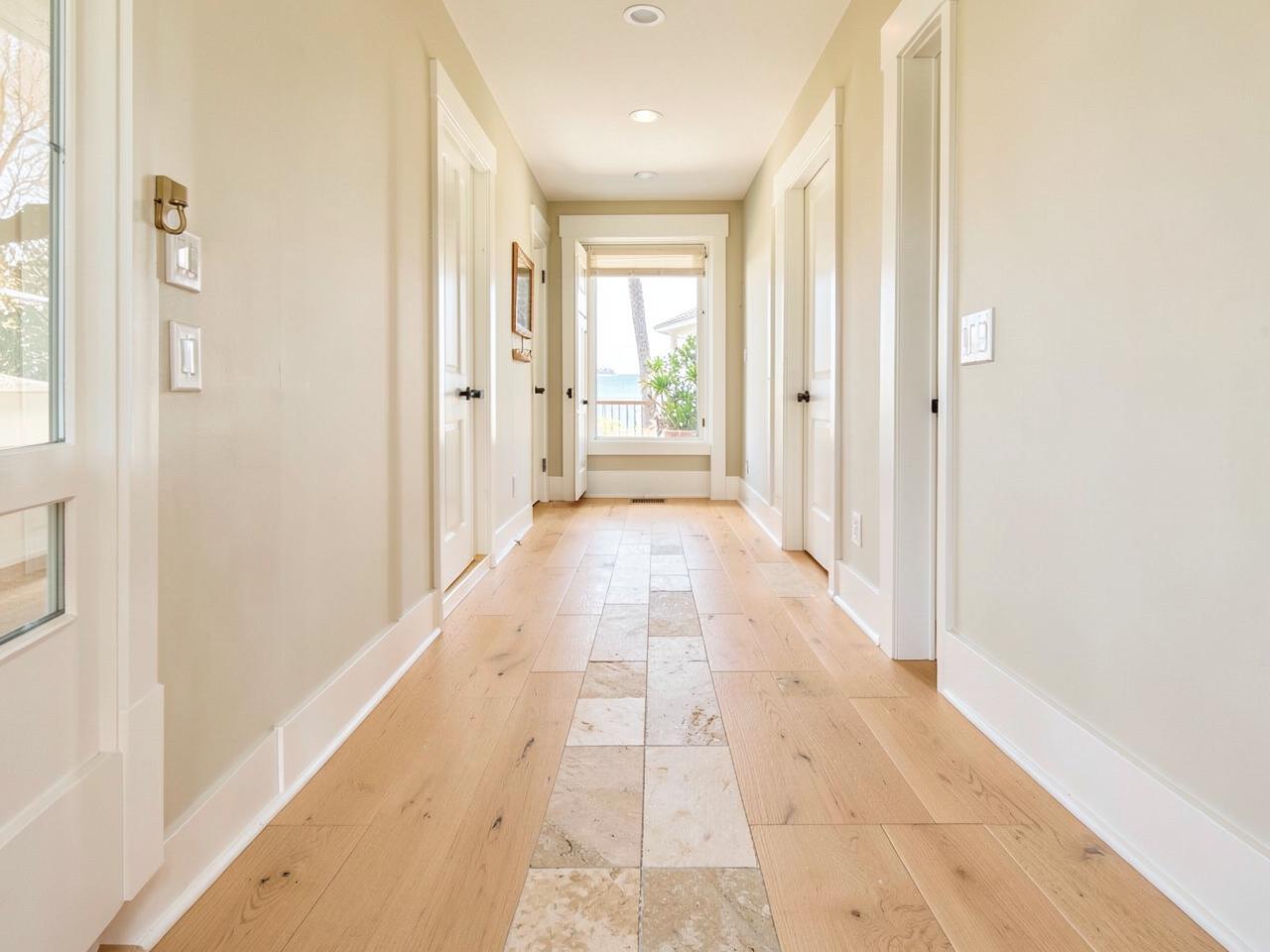 Wide-plank oak flooring meeting large-format stone tile in a renovated coastal home hallway